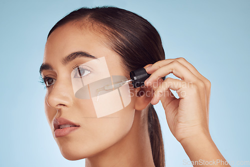 Image of Face, skincare and woman with serum dropper for beauty in studio isolated on a blue background. Cosmetics, model and essential oil, collagen and hyaluronic acid for dermatology, health and wellness