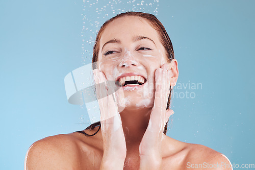 Image of Woman, cleaning face and soap with beauty, shower and hygiene with grooming isolated on blue background. Female model, sustainability and water drop with happiness, dermatology and skincare in studio