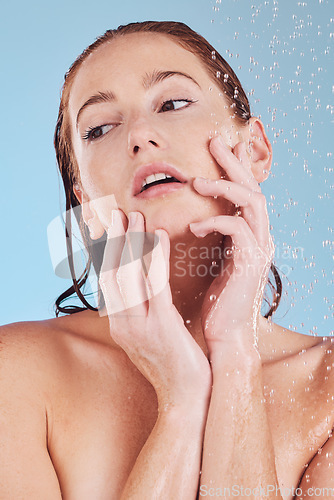 Image of Skincare, shower and girl with cleaning for self care or hygiene in studio or blue background. Woman, washing and water drops for beauty routine to relax or dermatology for hydration and wellness.