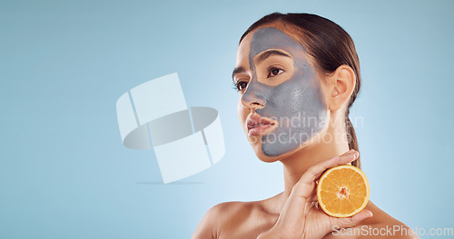 Image of Mockup, orange and mask for beauty with a woman in studio on a blue background for antiaging skincare. Face, facial and thinking with an attractive young person holding fruit for natural treatment