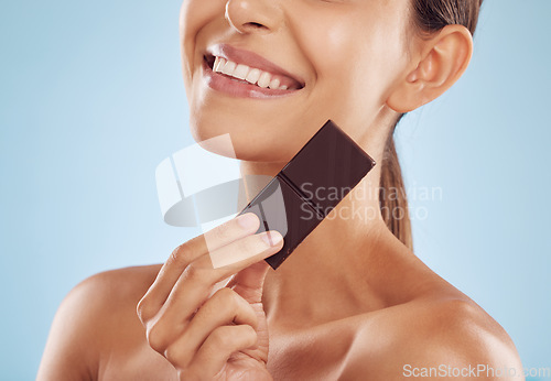 Image of Smile, skincare and woman with chocolate for beauty isolated on a blue background. Happy, candy and model with food, cacao and dessert, sweets and sugar for eating, cholesterol and natural cosmetics