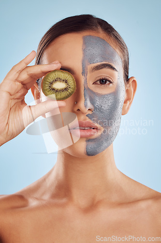 Image of Portrait, kiwi and mask for skincare with a woman in studio on a blue background for antiaging beauty. Face, facial and fruit with an attractive young female holding a berry for organic treatment