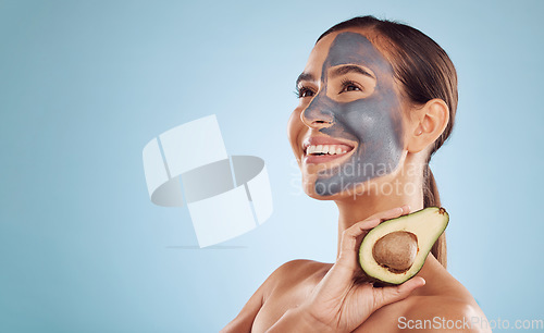 Image of Mockup, avocado and mask for beauty with a woman in studio on a blue background for antiaging skincare. Facial, smile and idea with an attractive young person holding a fruit for detox or treatment