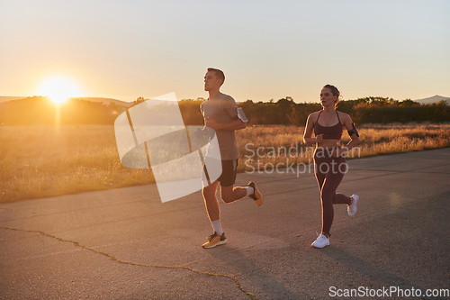 Image of A handsome young couple running together during the early morning hours, with the mesmerizing sunrise casting a warm glow, symbolizing their shared love and vitality