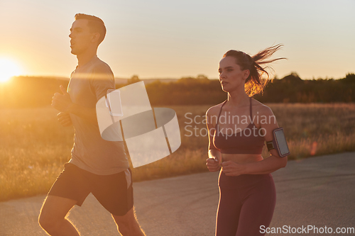 Image of A handsome young couple running together during the early morning hours, with the mesmerizing sunrise casting a warm glow, symbolizing their shared love and vitality