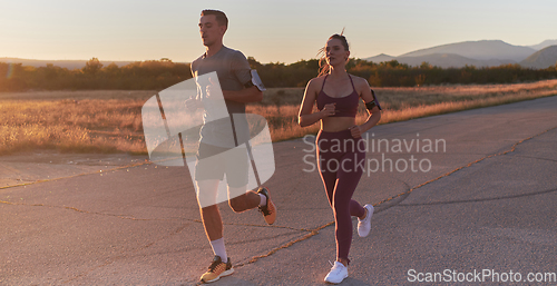 Image of A handsome young couple running together during the early morning hours, with the mesmerizing sunrise casting a warm glow, symbolizing their shared love and vitality