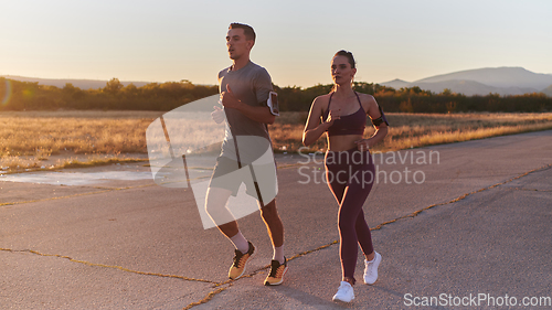 Image of A handsome young couple running together during the early morning hours, with the mesmerizing sunrise casting a warm glow, symbolizing their shared love and vitality