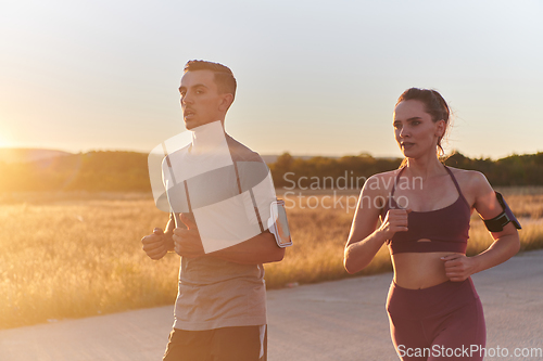 Image of A handsome young couple running together during the early morning hours, with the mesmerizing sunrise casting a warm glow, symbolizing their shared love and vitality