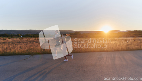 Image of A handsome young couple running together during the early morning hours, with the mesmerizing sunrise casting a warm glow, symbolizing their shared love and vitality