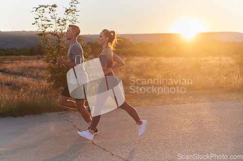 Image of A handsome young couple running together during the early morning hours, with the mesmerizing sunrise casting a warm glow, symbolizing their shared love and vitality