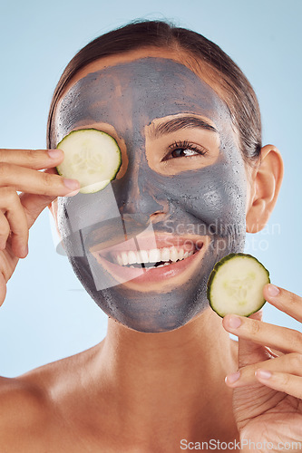 Image of Smile, cucumber and mask for beauty with a woman in studio on a blue background for antiaging skincare. Face, thinking and antioxidants with an attractive young female person posing for treatment