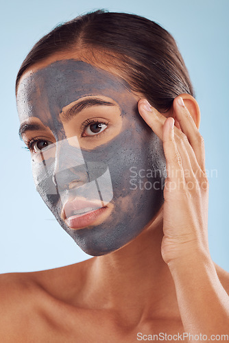 Image of Face mask, charcoal and beauty of woman as self care, cosmetic or facial treatment isolated in blue studio background. Skin, skincare and young female person clean, hydration and dermatology cream