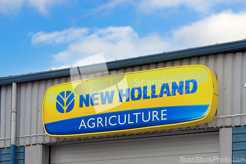 Image of New Holland Agriculture Logo at Dealership with Beautiful Sky