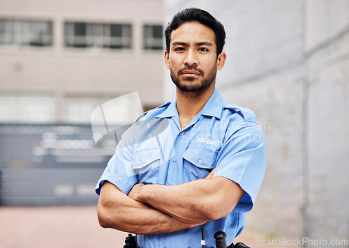 Image of Portrait, man and security guard with arms crossed for police service, protection and safety in city. Law enforcement, bodyguard and serious asian male officer in blue uniform outdoor for town patrol