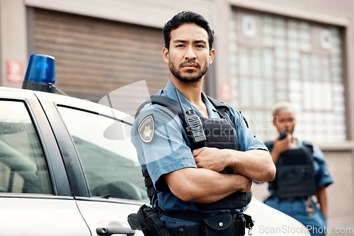 Image of Asian man, police and arms crossed in city for law enforcement, protection or street safety. Portrait of serious male person, security guard or cop ready for justice or crime on patrol in urban town