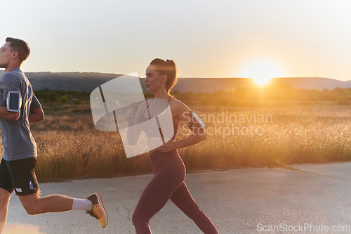 Image of A handsome young couple running together during the early morning hours, with the mesmerizing sunrise casting a warm glow, symbolizing their shared love and vitality