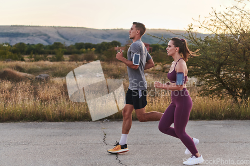 Image of A handsome young couple running together during the early morning hours, with the mesmerizing sunrise casting a warm glow, symbolizing their shared love and vitality