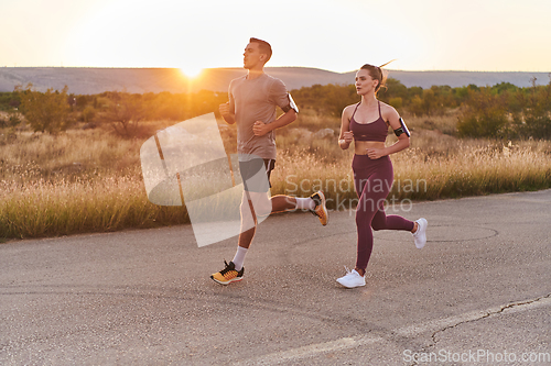 Image of A handsome young couple running together during the early morning hours, with the mesmerizing sunrise casting a warm glow, symbolizing their shared love and vitality