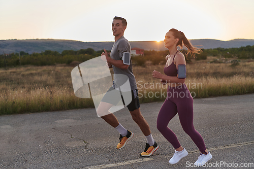 Image of A handsome young couple running together during the early morning hours, with the mesmerizing sunrise casting a warm glow, symbolizing their shared love and vitality