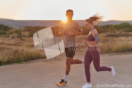 Image of A handsome young couple running together during the early morning hours, with the mesmerizing sunrise casting a warm glow, symbolizing their shared love and vitality