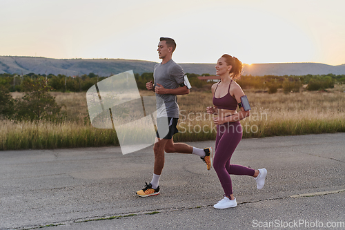 Image of A handsome young couple running together during the early morning hours, with the mesmerizing sunrise casting a warm glow, symbolizing their shared love and vitality