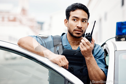 Image of Asian man, police and walkie talkie for radio in city communication, reinforcement or emergency. Serious male person or security guard by cop car and calling backup for crime on patrol in urban town