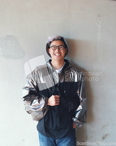 Image of Portrait, fashion and Asian man with a smile, streetwear and stylish outfit against a wall background. Male person, happy model and student with glasses, trendy clothes and happiness with confidence