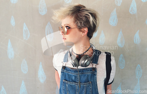 Image of Fashion, music and a gen z woman thinking in studio on a rain wallpaper background for trendy style. Cyberpunk, idea and headphones with an attractive young female person looking cool or edgy