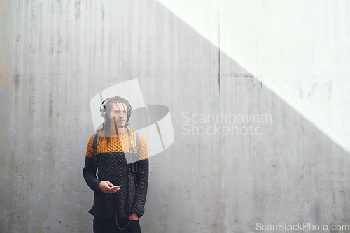 Image of Man, student and smartphone with headphones and music on university campus, future mindset against wall background. Gen z, education and male person at college, mockup space and listen to podcast