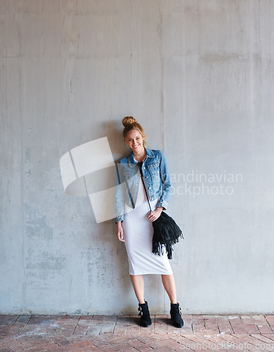 Image of Portrait, travel and smile with a woman on a concrete wall as a tourist leaning against a building in the city. Fashion, tourism or travelling with a happy and trendy young person in Norway for style