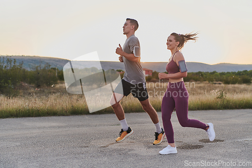 Image of A handsome young couple running together during the early morning hours, with the mesmerizing sunrise casting a warm glow, symbolizing their shared love and vitality