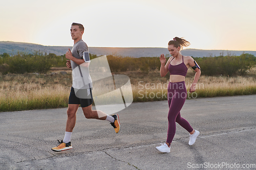 Image of A handsome young couple running together during the early morning hours, with the mesmerizing sunrise casting a warm glow, symbolizing their shared love and vitality