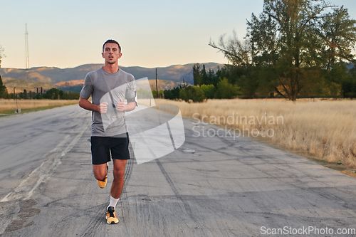 Image of A young handsome man running in the early morning hours, driven by his commitment to health and fitness