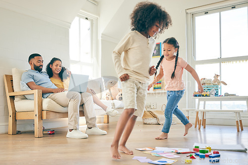 Image of Big family, toys and children running with parents on a laptop .in lounge at home together for creative fun. Living room, happy and development of kids on carpet floor with games by mom and dad