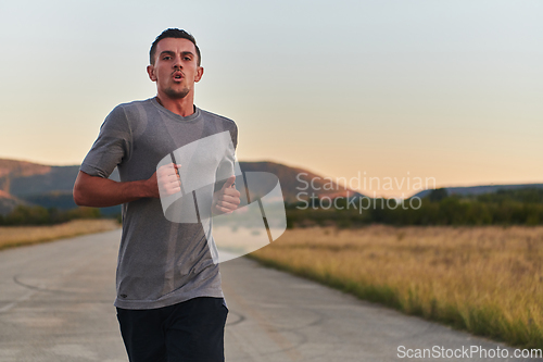 Image of A young handsome man running in the early morning hours, driven by his commitment to health and fitness