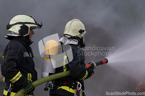 Image of Firefighters using water fog type fire extinguisher to fighting with the fire flame to control fire not to spreading out. Firefighter industrial and public safety concept.