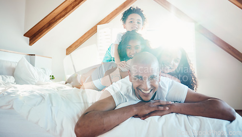 Image of Pile, family and portrait in home bedroom, bonding and sunshine with lens flare. Face, happy and children with father, mother and parents on bed with love, care and quality time for game together.