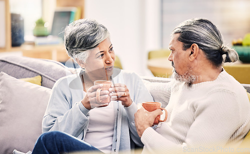 Image of Coffee, conversation and senior couple on a sofa for bond, discussion or sharing gossip in their home. Love, tea and old people relax on couch for break, speaking or did you know drama in living room