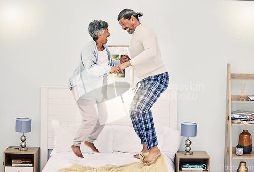 Image of Happy, playful or old couple jumping on bed to relax, enjoy holiday or fun morning together at home. Playing, silly senior woman or elderly man laughing or bonding with love or smile in retirement