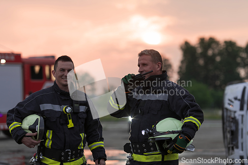 Image of fireman using walkie talkie at rescue action fire truck and fireman's team in background.