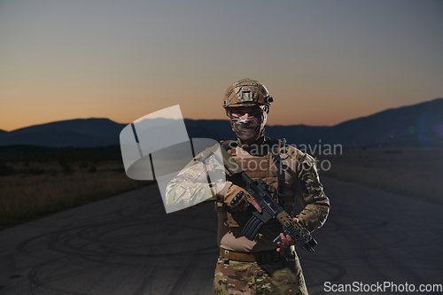 Image of A professional soldier in full military gear striding through the dark night as he embarks on a perilous military mission