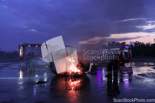 Image of Firefighters using water fire extinguisher to fighting with the fire flame in car accident. Firefighter industrial and public safety concept rescue in night.