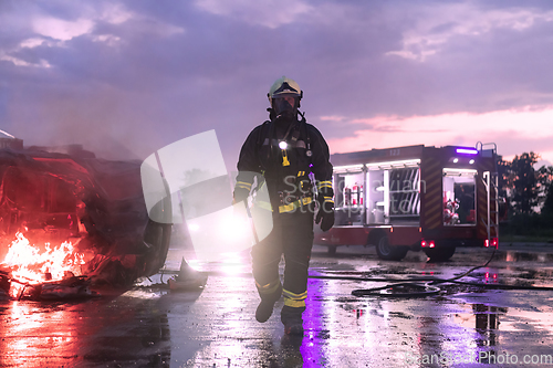 Image of Portrait of a heroic fireman in a protective suit. Firefighter in fire fighting or car accident rescue operation in dusk or night.