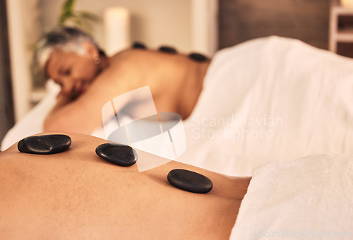 Image of Closeup, spa and stone massage on back of people for skincare cosmetics, holistic therapy and muscle healing at beauty salon. Relax, wellness resort and self care of hot rocks for zen, peace or detox