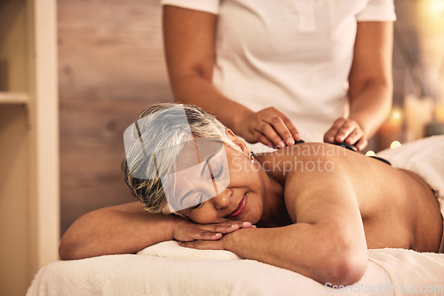 Image of Woman, spa and stone massage for healing back muscle, skincare treatment and holistic therapy at beauty salon. Mature female person relax at wellness resort with rocks for self care, detox and zen