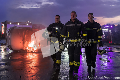 Image of Brave Firefighters Team Walking to the Camera. In Background Paramedics and Firemen Rescue Team Fight Fire in Car Accident, Insurance and Save Peoples Lives concept.