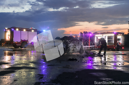 Image of Firefighters using water fire extinguisher to fighting with the fire flame in car accident. Firefighter industrial and public safety concept rescue in night.