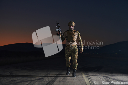 Image of A professional soldier in full military gear striding through the dark night as he embarks on a perilous military mission