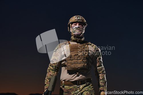 Image of A professional soldier in full military gear striding through the dark night as he embarks on a perilous military mission