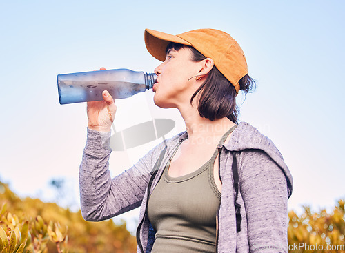 Image of Break, fitness and woman drinking water in nature for wellness, health and after training. Hydration, rest and an athlete with a bottle to drink after running, hiking or cardio on the mountain